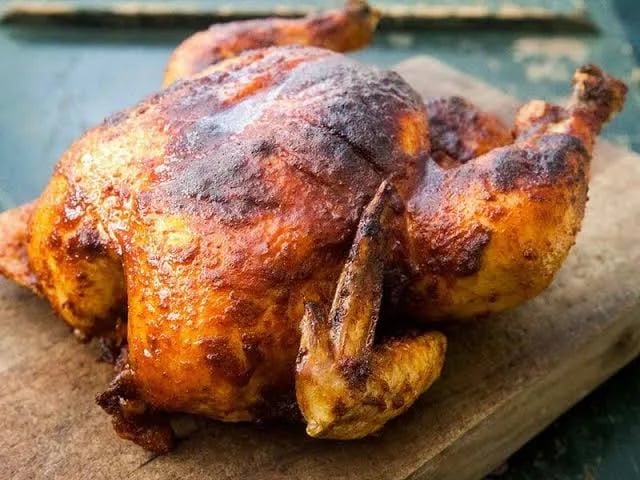 Poulet rôti entier et doré, posé sur une planche en bois