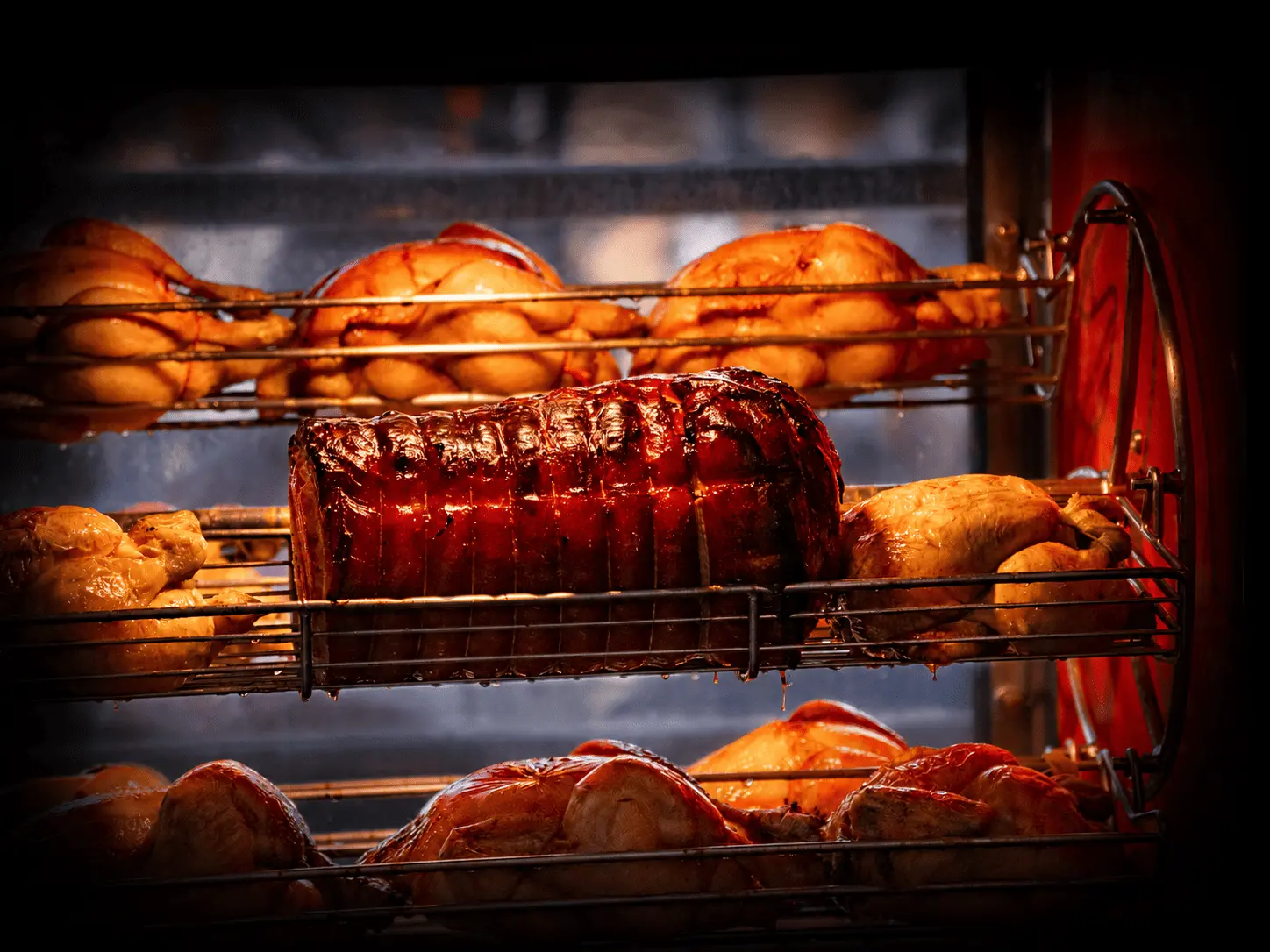 Poulets et rôtis dorés en cuisson sur les broches de la rôtisserie